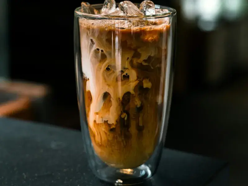 A tall glass of cold coffee, poured over ice and layered into milk