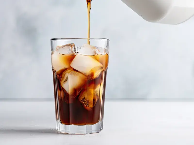 Black coffee poured over a tall glass packed with ice